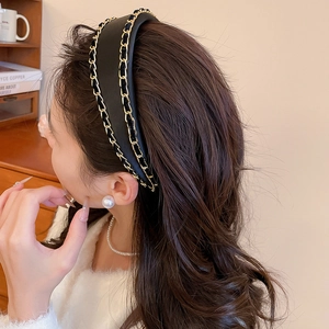 Close-up of black leather padded headband with elegant double gold chain link trim