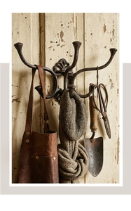 Detailed close-up of retro cast iron wall hook featuring ornate scrollwork on aged wood
