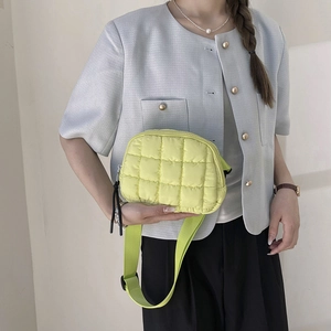 Detail of yellow quilted crossbody bag with square pattern and adjustable wide strap
