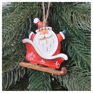 Close-up of Santa Claus on sled Christmas ornament hanging on a green tree branch