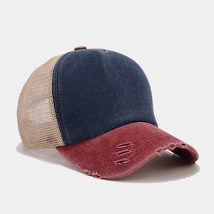 Detail of distressed mesh trucker hat showing burgundy brim and blue denim crown