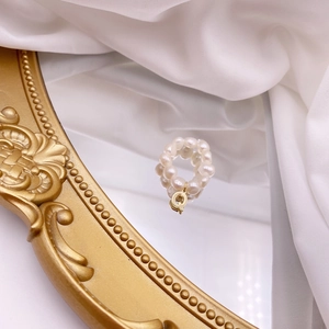 Detailed macro view of natural freshwater pearl elastic ring with a gold letter Q charm
