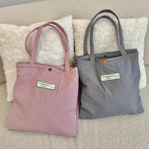 Detail of plaid tote bags with embroidered patches and snap button closure