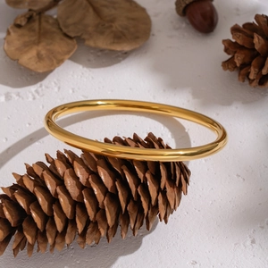 Minimalist 18K gold plated round bangle displayed on a natural pinecone setting