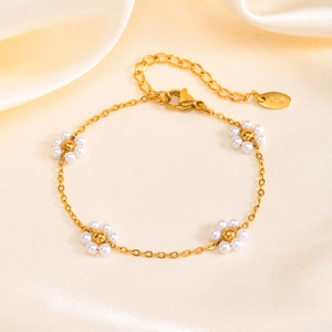 Detailed shot of golden flower bracelet with pearls and K18 hallmark on silk background