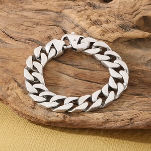 Vintage stainless steel Cuban link bracelet with lobster clasp on natural wood stand