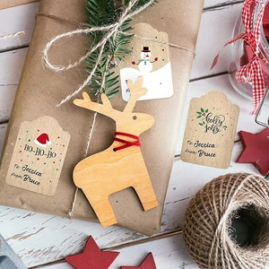 Christmas kraft paper gift tags with wooden reindeer pendants on white wood background