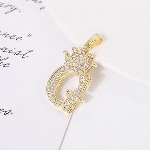 Macro shot of gold-plated G-letter pendant with crown design and shimmering zircons