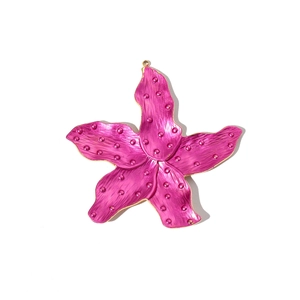 Macro view of pink flower pendant with gold edges and raised dot texture details