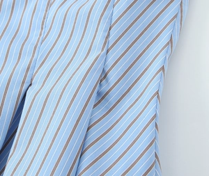 Gros plan sur le tissu en popeline à rayures verticales bleues et brunes détaillées