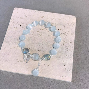 Détail macro de perles œil-de-chat bleues et breloque papillon en zircon sur bracelet perlé