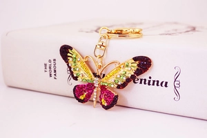 Macro detail of butterfly keychain featuring colorful rhinestones and gold metal frame