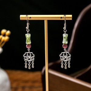 Detail of vintage silver earrings featuring green jade-like beads and long tassels