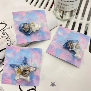 Détail de barrettes océan en résine avec coquillages naturels et perles sur carte