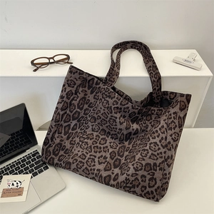 Detailed close-up of a large leopard print suede tote bag on a minimalist desk workspace