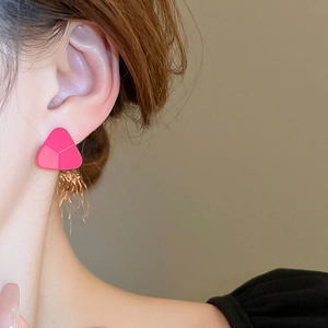 Gros plan de boucles d'oreilles triangles roses minimalistes portées par une femme