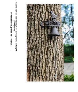 Detail of rustic cast iron welcome bell with bird statue mounted on tree in a garden
