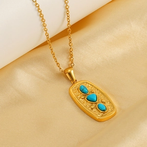 Detailed macro view of three turquoise stones set in a gold-plated hammered rectangle pendant