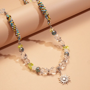 Détail d'un collier de perles bohème avec corde colorée et pendentif soleil argenté