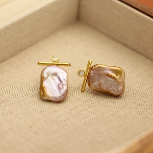 Macro detail of baroque pearl earrings with gold plating and sparkling zircon accents