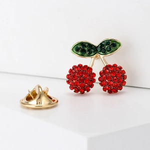 Cute cartoon cherry brooch with sparkling red and green crystals on white background