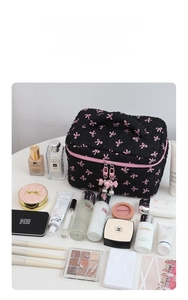 Macro detail of quilted black makeup bag with pink bow pattern and pearl zipper charm