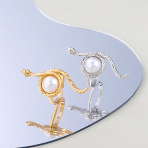 Macro detail of snake-shaped rings in gold and silver finish with elegant white pearl