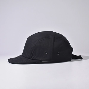 Detail view of a black 5-panel camp cap showing side metal eyelets and adjustable strap