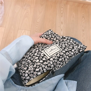Close-up of black and white floral cotton clutch bag with zipper and decorative label