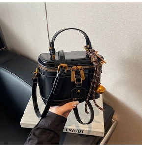 Detail of black box bucket bag with gold hardware and branded Chan'2ab logo tag