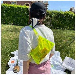 Outdoor shot showing back view of neon yellow transparent PVC shoulder bag on a model