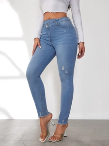 Details einer High-Waist-Jeans mit unregelmäßigem Kreuzbund und Fransensaum