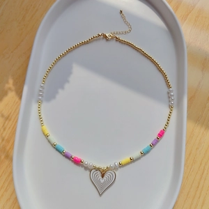 Detailed view of colorful clay beads and a white heart pendant necklace on tray