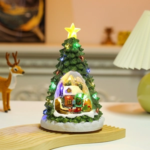 Detail of glowing Christmas tree miniature with red train and snowy house decor
