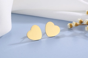 Gros plan de boucles d'oreilles cœur en acier inoxydable doré sur fond bleu élégant