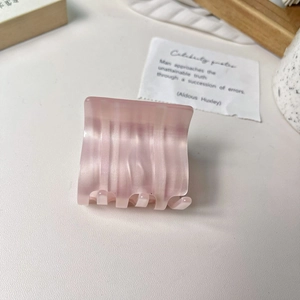 Detailed macro view of pink iridescent acetate hair claw clip with pearlescent finish