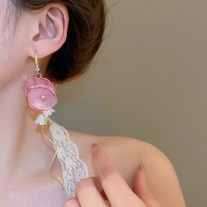 Close-up of pink fabric flower earrings with golden wave tassels and pearls on a model
