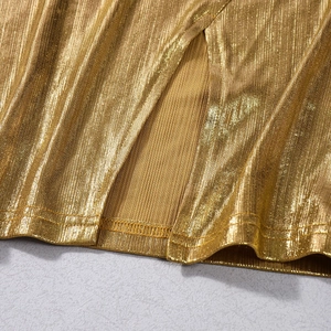 Vue détaillée du tissu plissé doré métallisé avec une fente haute à l'ourlet