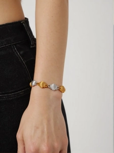 Detail of two-tone gold and silver shell link bracelet worn on wrist with textured surface
