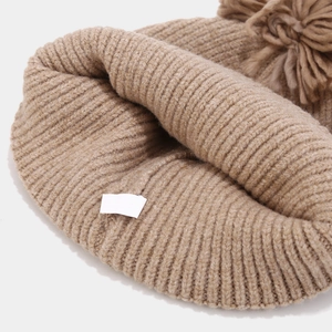 Detail view of khaki ribbed knit beanie with a soft matching faux fur pom-pom on top