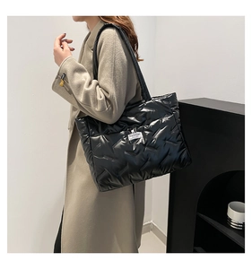 Macro detail of black quilted tote bag showing soft padded texture and fashion logo tag