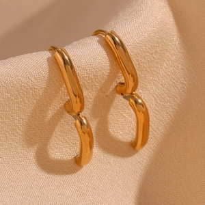 Macro view of minimalist 18K gold plated stainless steel mini hoop earring on beige fabric