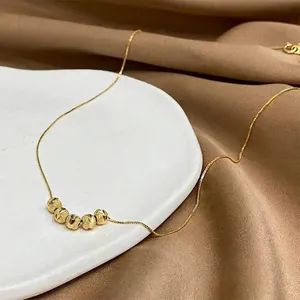 Minimalistische Goldkette mit fünf mattierten Perlen auf feiner Kette über Seide