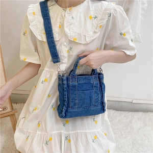 Detailed close-up of blue denim handbag featuring contrast stitching and adjustable strap