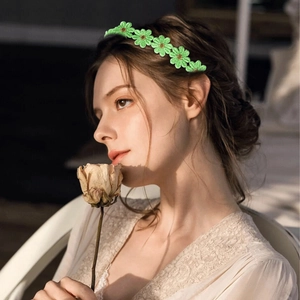 Detail of green floral daisy headband with yellow center on model for girls