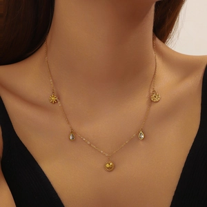 Gold plated stainless steel necklace with sun and drop charms on a female model