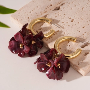 Vue macro détaillée des boucles d'oreilles fleur en acrylique rouge foncé avec anneaux dorés
