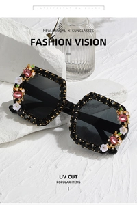 Detail view of square black sunglasses with crystal accents and white flower ornaments