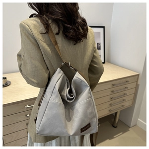Close-up of gray large capacity tote bag with brown shoulder strap on a female model