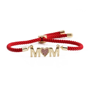 Adjustable red cord bracelet featuring gold MOM lettering with a ruby red heart gem